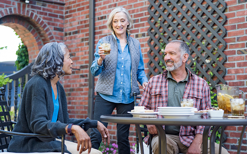 Photo of two older women and an older man eating and talking together